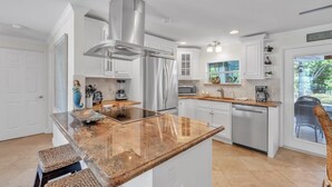 Une cuisine moderne avec des meubles blancs, des appareils en acier inoxydable et un îlot central.