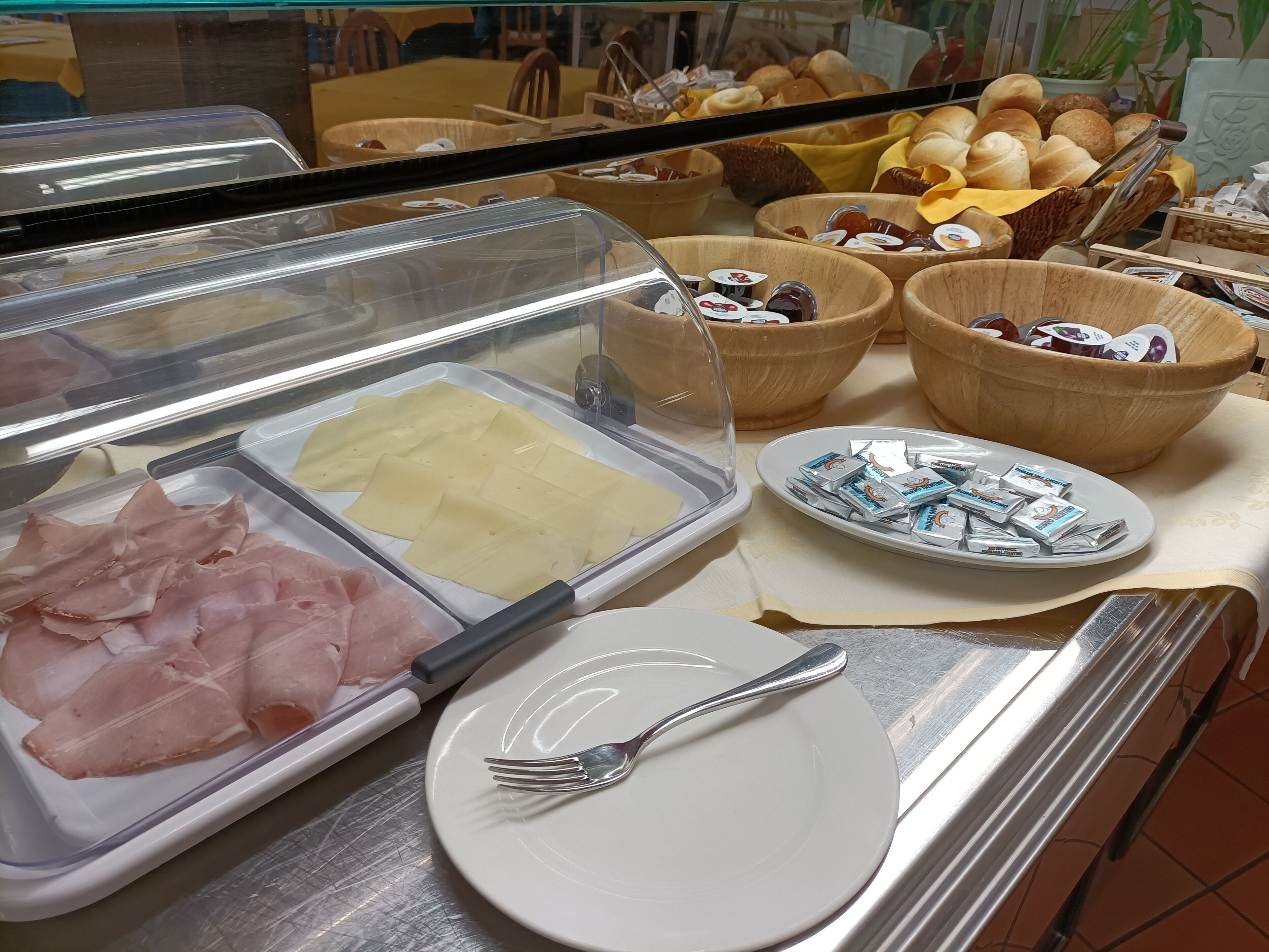 Buffet com diversas opções de comida, incluindo carnes fatiadas, queijos e doces.