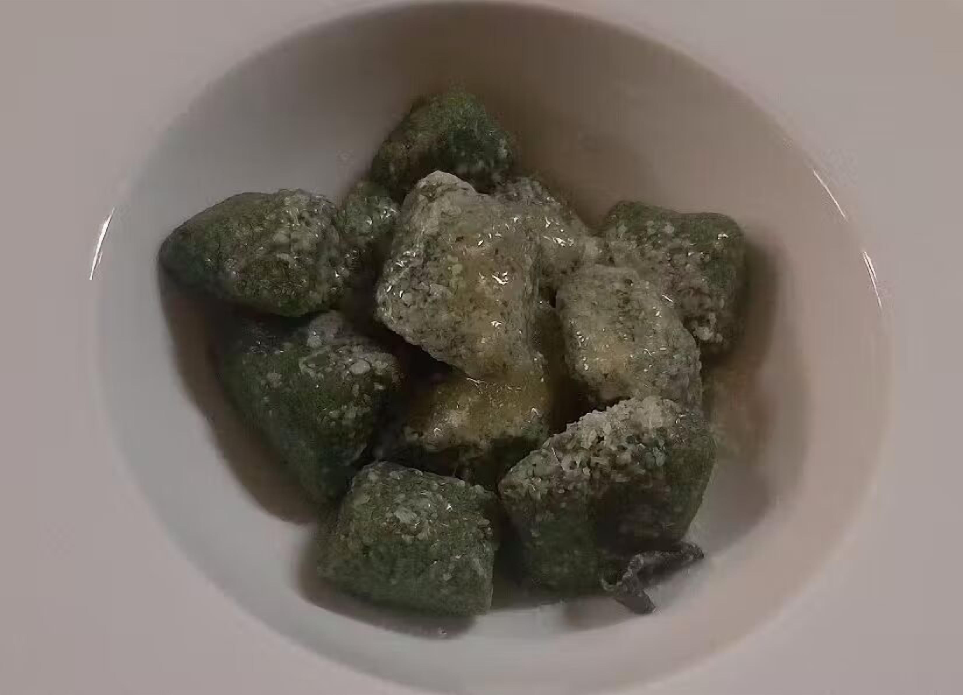 Un bol contenant des aliments de couleur gris-verdâtre et de forme irrégulière.