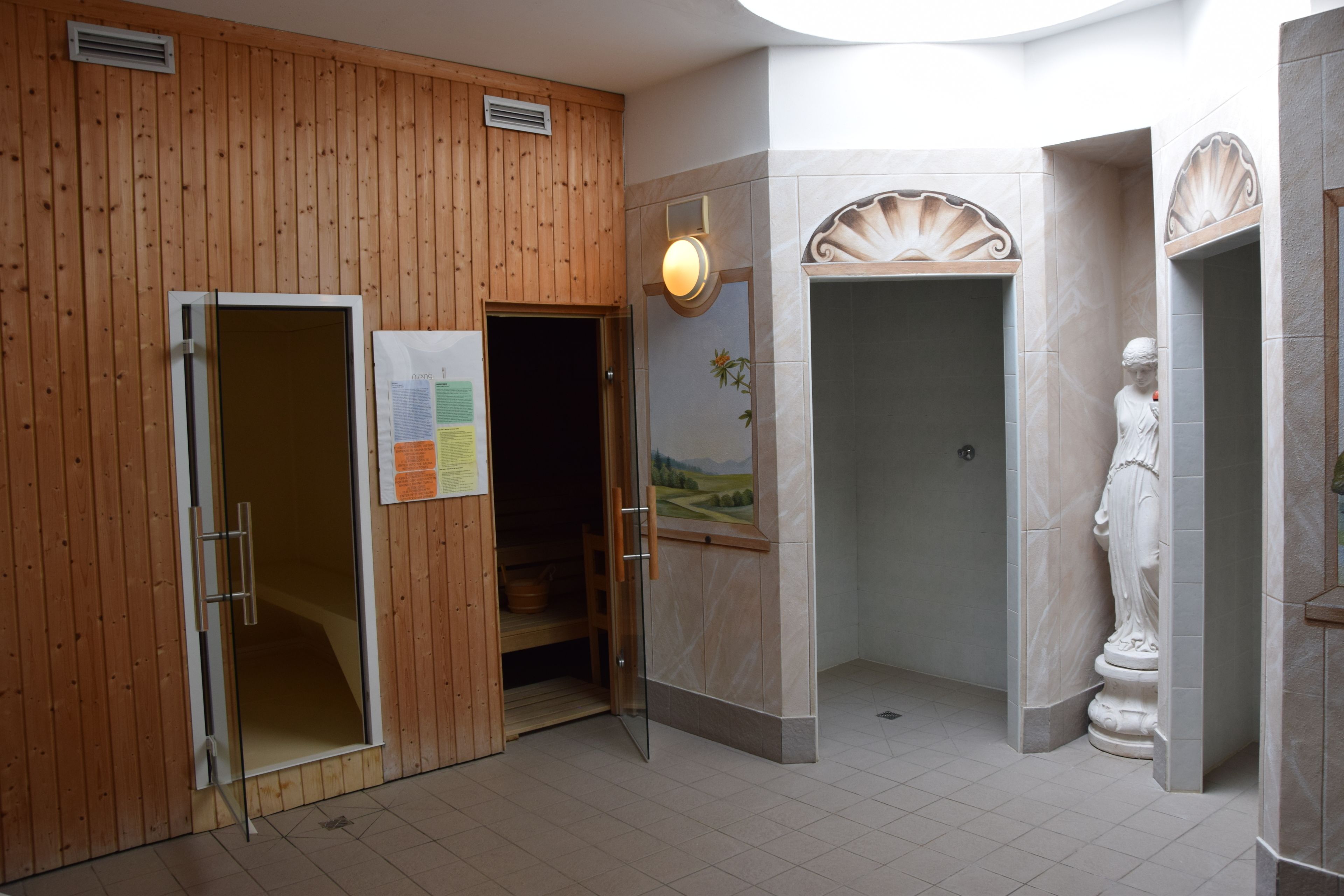 A sauna room with wooden walls, a glass door, and a statue.