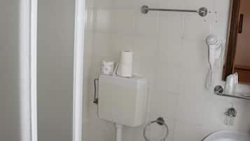 Et badeværelse med toilet, bidet, vask og et håndklædetørrestativ.