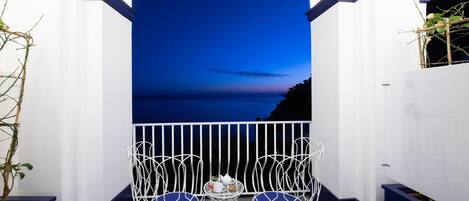 A balcony with two white wire chairs and a small table with a teapot and cups.
