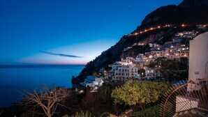 Un pueblo costero al atardecer, con edificios en una ladera que dominan el mar.
