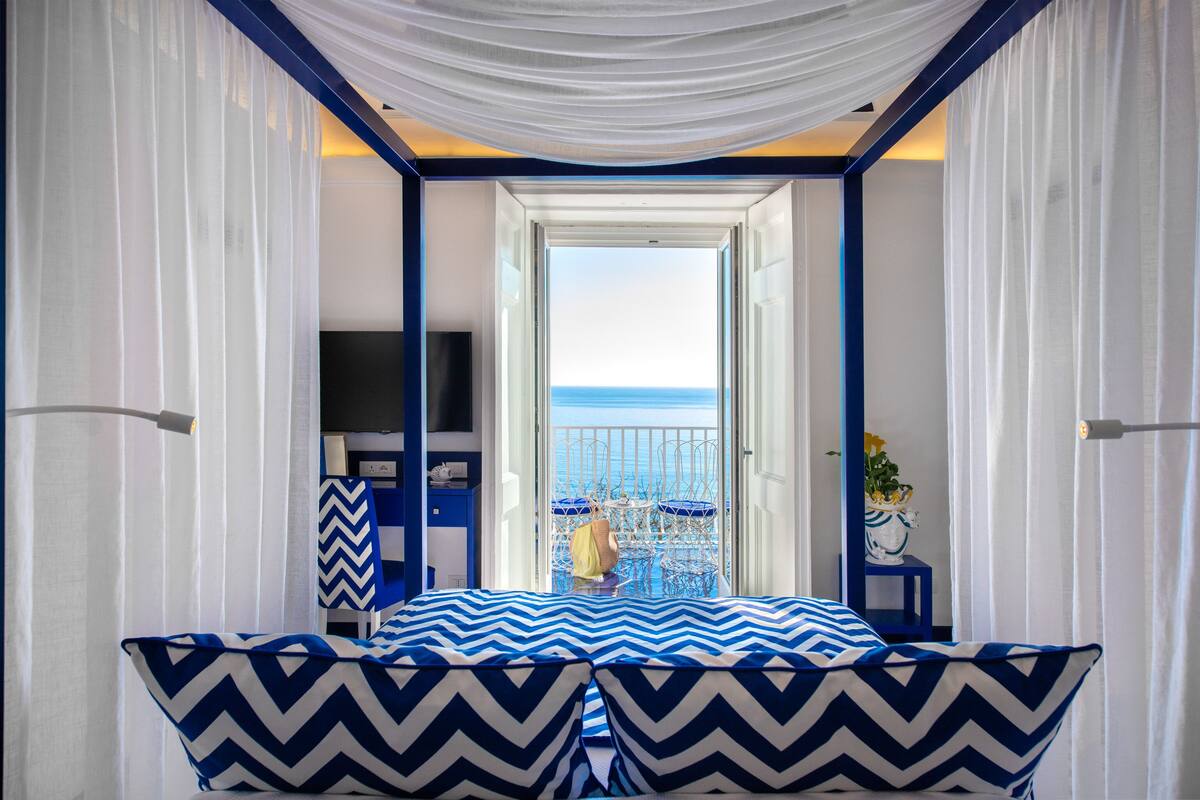 A room with a bed, a TV, and a view of the sea.