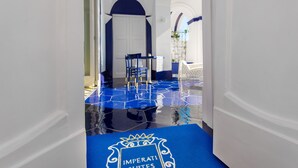 Un pasillo con alfombra azul que conduce a una habitación con puerta blanca.