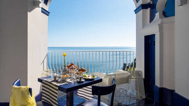 Un balcón con una mesa dispuesta para el desayuno, con vistas al mar.