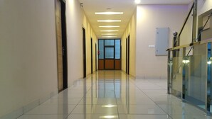Un couloir moderne et bien éclairé, doté d’un sol brillant, d’un éclairage encastré et d’un spot lumineux bleu au plafond.