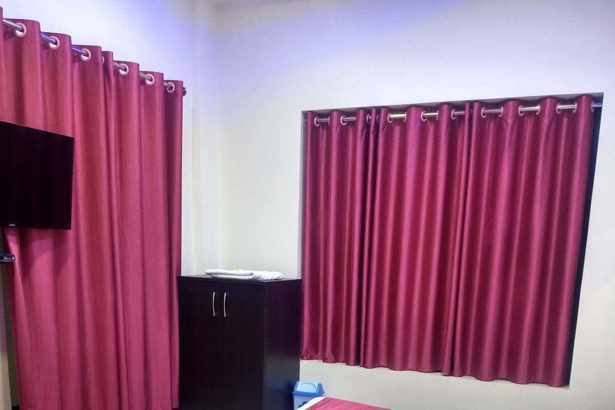 A hotel room with a bed, a TV, a wardrobe, and a desk.