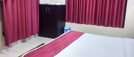 A hotel room with a bed, a TV, a wardrobe, and a desk.