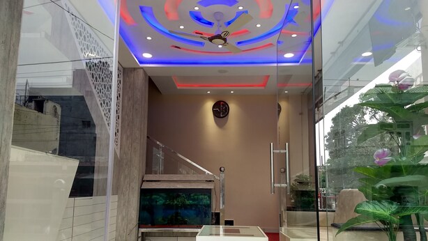 Un hall d’entrée moderne avec une cloison en verre, un comptoir d’accueil blanc, un ventilateur de plafond et un grand aquarium.