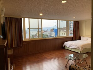A hotel room with a large window, wooden flooring, a bed, a glass table, and a TV. - Da Tong B&B (Yuchi)