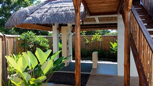 A wooden structure with a thatched roof, a staircase, and a view of a garden with tropical plants. - Samari Hill Villas (Tejakula)