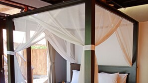 A four-poster bed with white linens and a canopy, wooden flooring, and a view of the outdoors. - Samari Hill Villas (Tejakula)