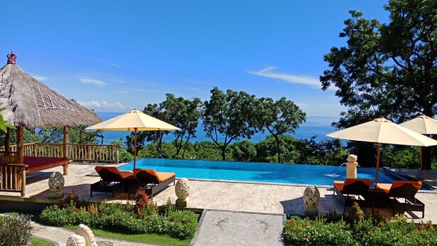 An infinity pool with a view of the ocean, surrounded by lounge chairs and umbrellas. - Samari Hill Villas (Tejakula)