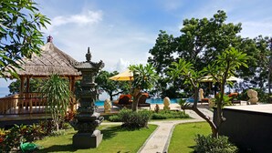 A tropical resort with a thatched-roof gazebo, a stone fountain, and a pool area with lounge chairs. - Samari Hill Villas (Tejakula)