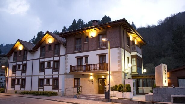 Un hotel de estilo arquitectónico tradicional, con un balcón en el segundo piso, un letrero que indica que es un hotel y una entrada bien iluminada.