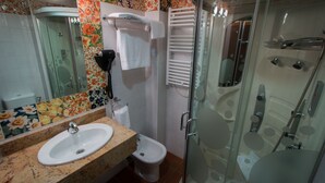Un baño con ducha de vidrio, inodoro y lavamanos con encimera de mármol.