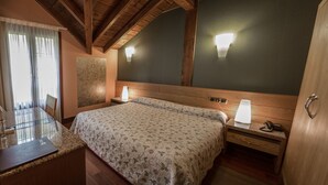 Un dormitorio con cama, lámparas de noche, cabecera de madera, mesita de noche, escritorio con una computadora portátil y ventana con cortinas.