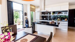 Une cuisine moderne avec des meubles blancs, un plan de travail noir et un meuble à vin intégré.