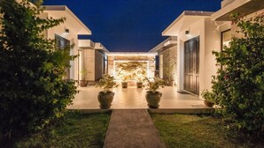 Une maison moderne dotée d’un patio central, de plantes en pot et d’une entrée bien éclairée.