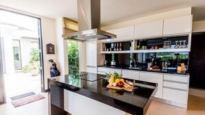 Une cuisine moderne dotée d’un îlot central, de meubles blancs et d’une variété d’ustensiles de cuisine et d’appareils électroménagers.