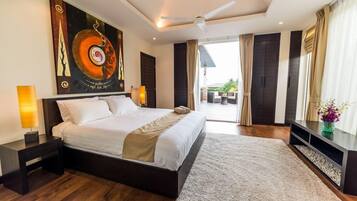 A modern hotel bedroom with a large bed, a ceiling fan, a view of the outdoors, and a painting on the wall.