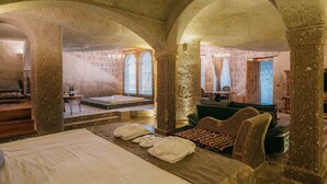 Una habitación con una cama, una mesa de masaje y una zona de estar con un banco y cojines.