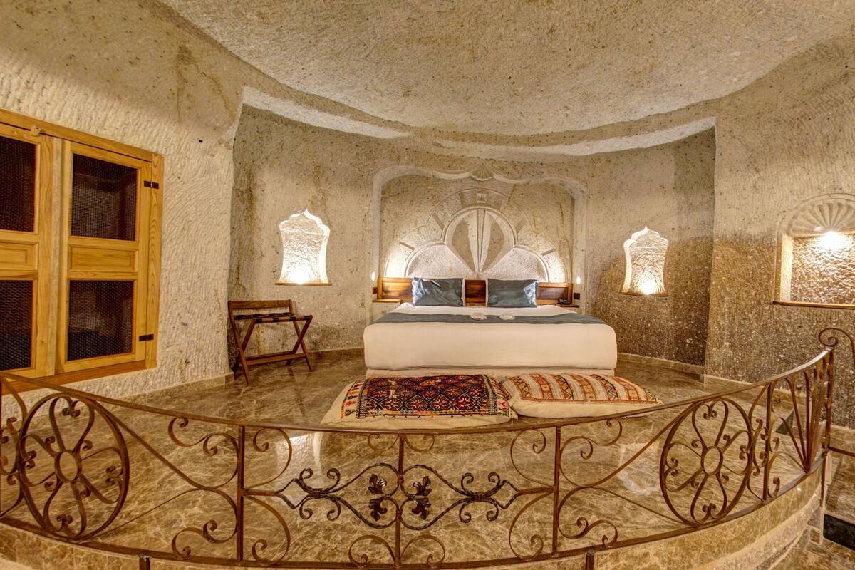 Una habitación con una cama grande, un banco de madera y una barandilla curva.