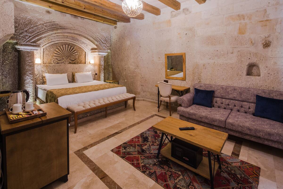 Una habitación acogedora con una cama, un sofá, una mesa de madera y un escritorio.
