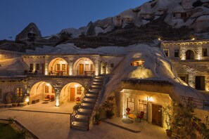 A hotel with a unique cave-like architecture, featuring multiple levels, a central staircase, and outdoor seating areas. - Lunar Cappadocia Hotel (Nevsehir)