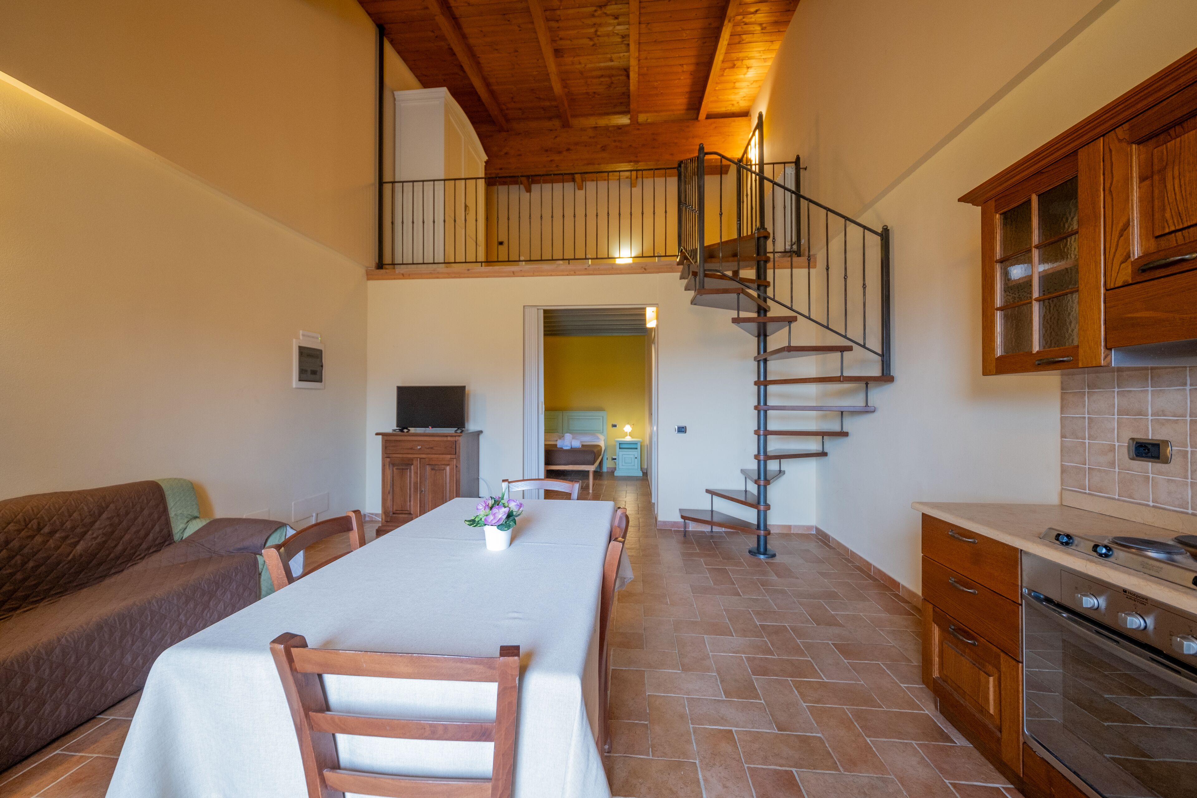 Eine geräumige Küche mit einer Holztreppe, einem Essbereich mit Tisch und Stühlen sowie einem gemütlichen Wohnbereich mit einer Couch.