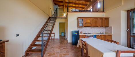 A spacious kitchen with wooden cabinets, a dining table, and a staircase leading to an upper level.