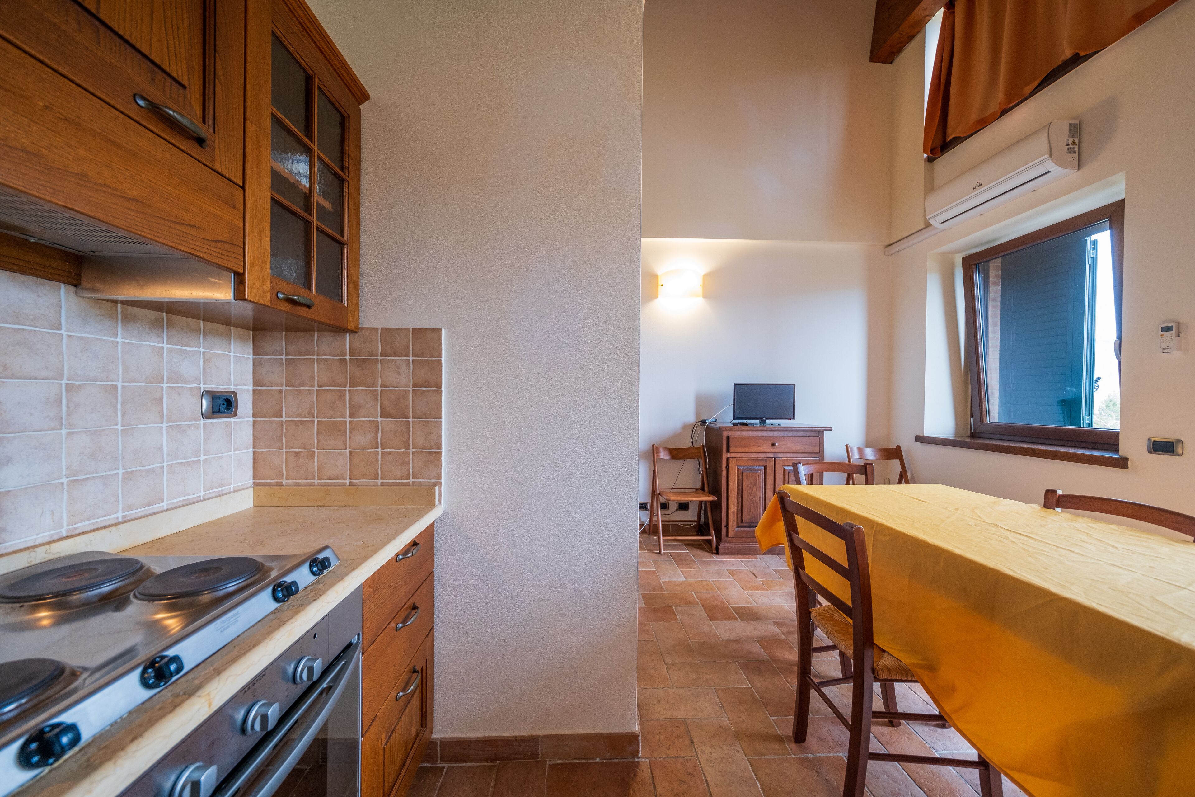 A compact kitchen with a stove, cabinets, and a dining area with a table and chairs.