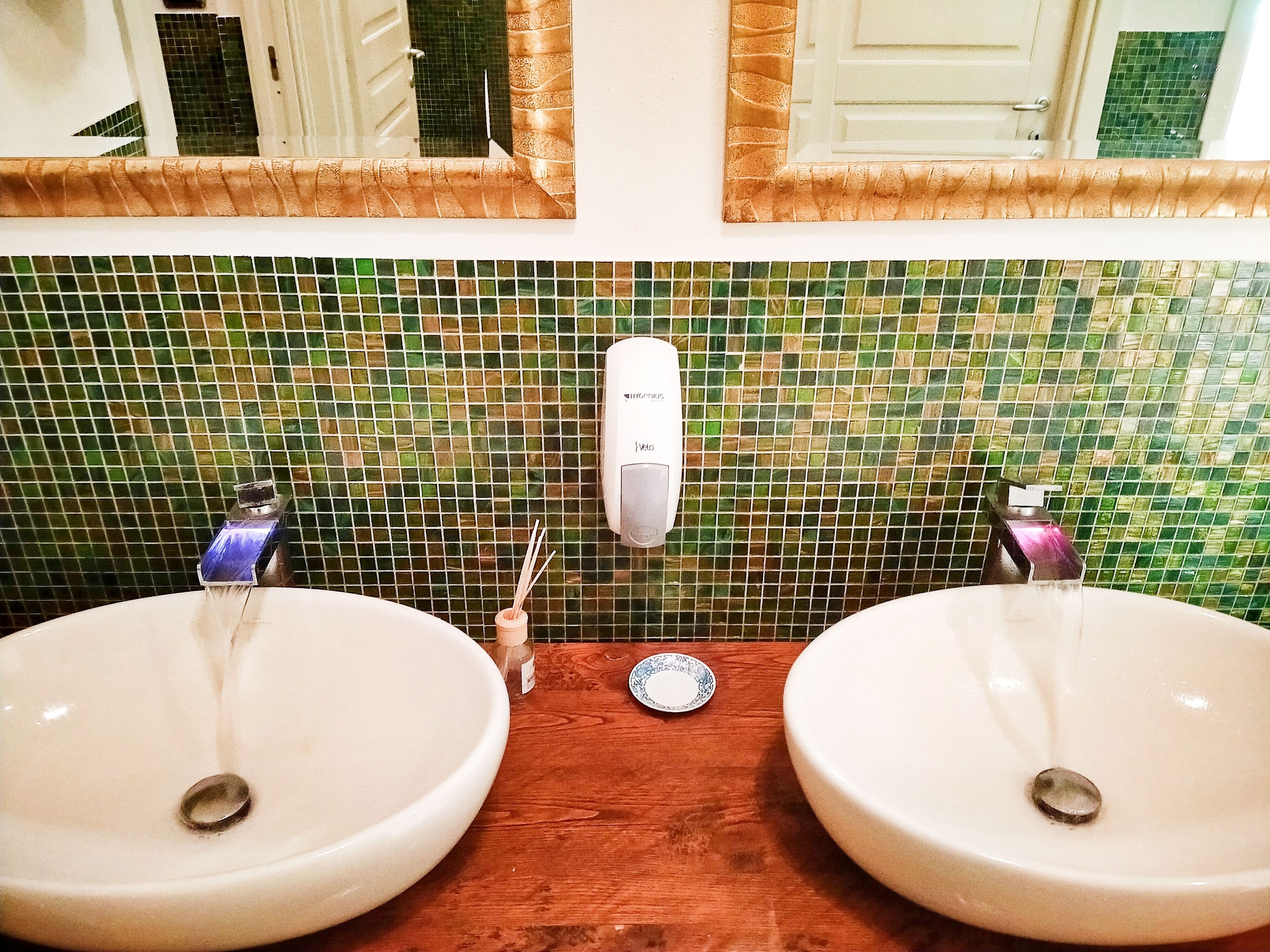 Un baño con dos lavamanos, un dispensador de jabón y un espejo.