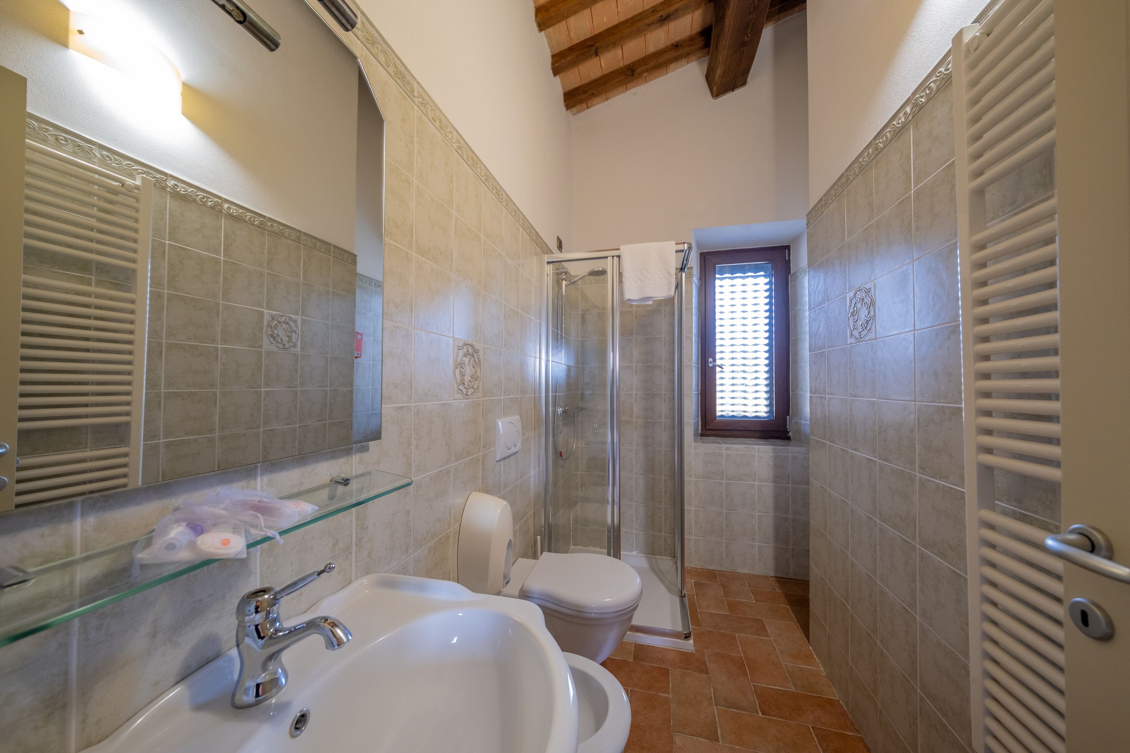 A bathroom with a glass shower enclosure, a white sink, and a toilet.