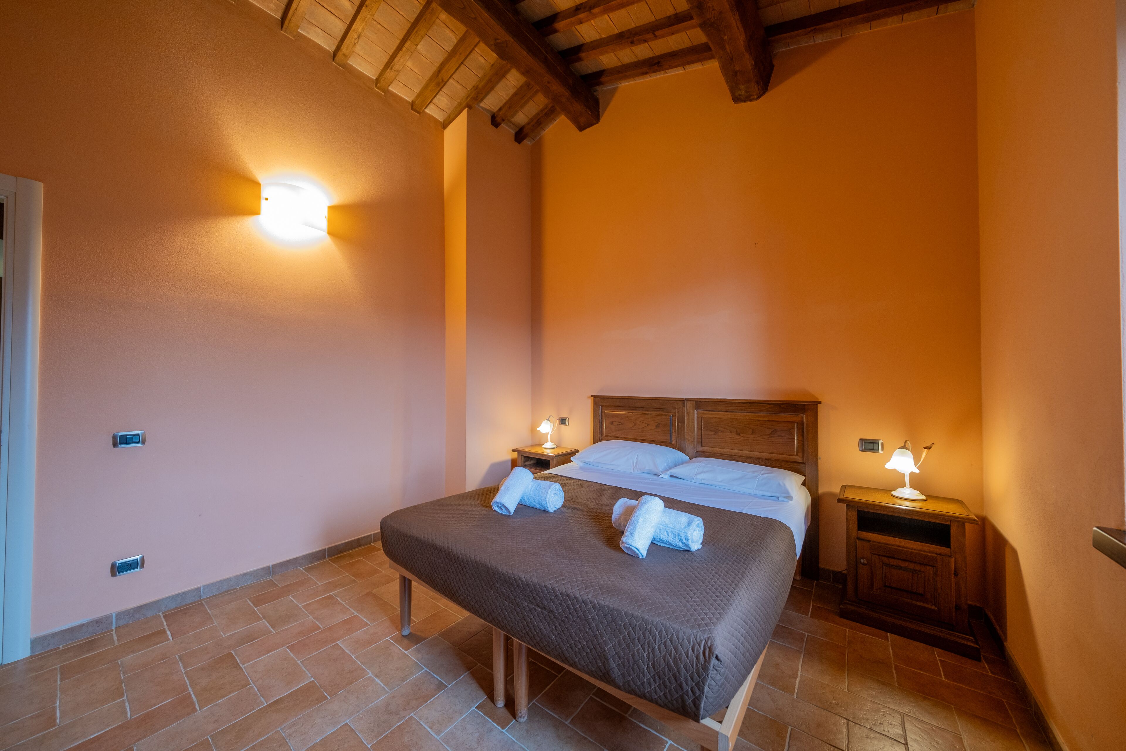 A bedroom with a large bed, two bedside tables with lamps, and a wooden headboard.