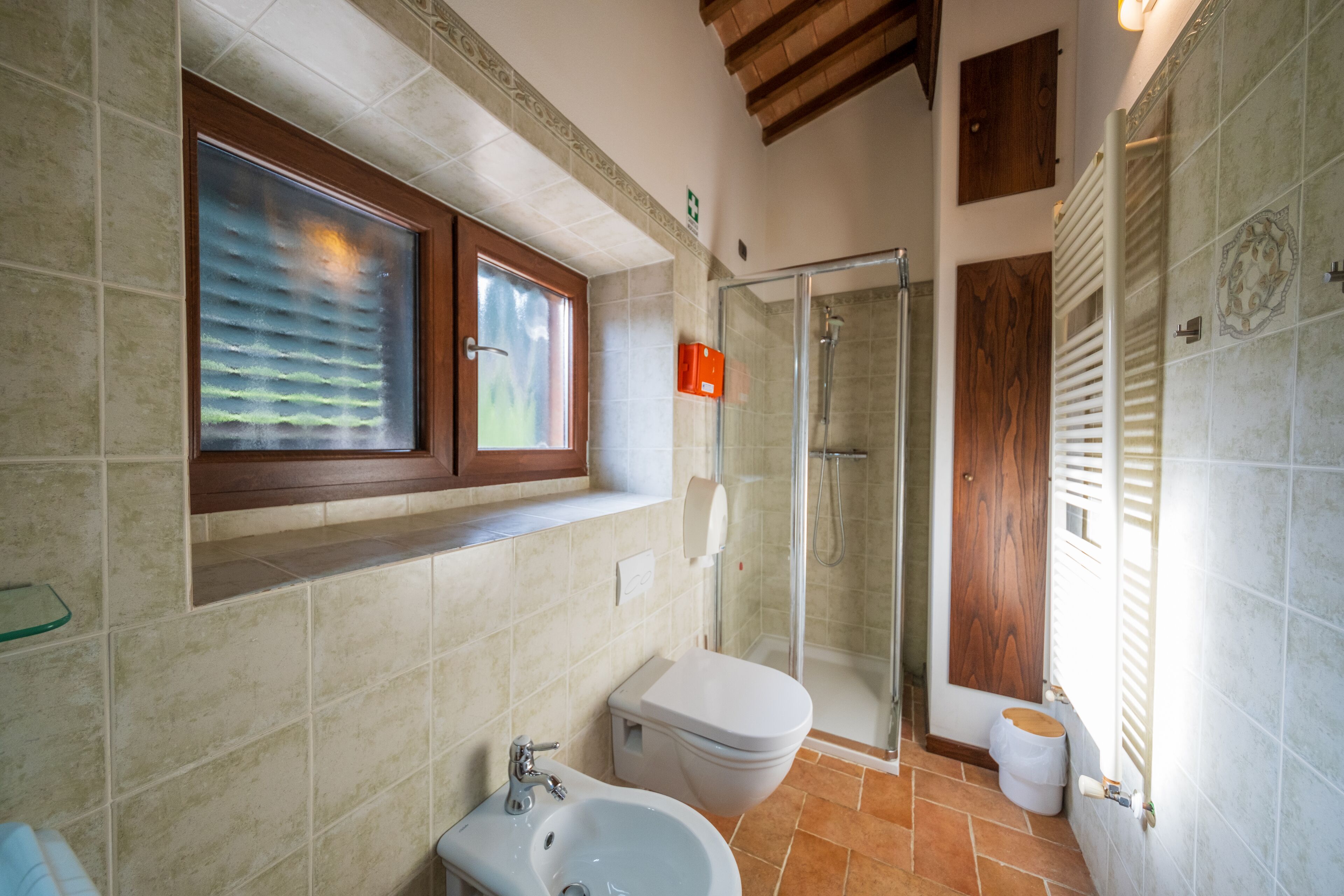 A bathroom with a glass shower enclosure, a toilet, a bidet, and a sink.