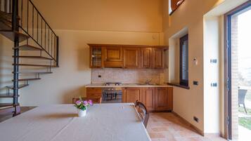 A kitchen with wooden cabinets, a dining table with a vase of flowers, and a staircase.