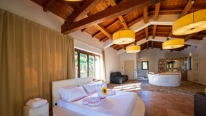 Un dormitorio espacioso con una cama grande, techo de madera y pared de piedra al fondo.
