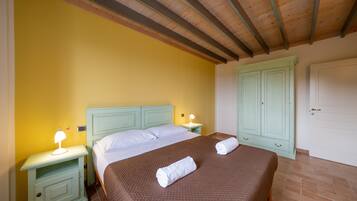 Un dormitorio con cama, dos mesitas de noche, un armario y una puerta.