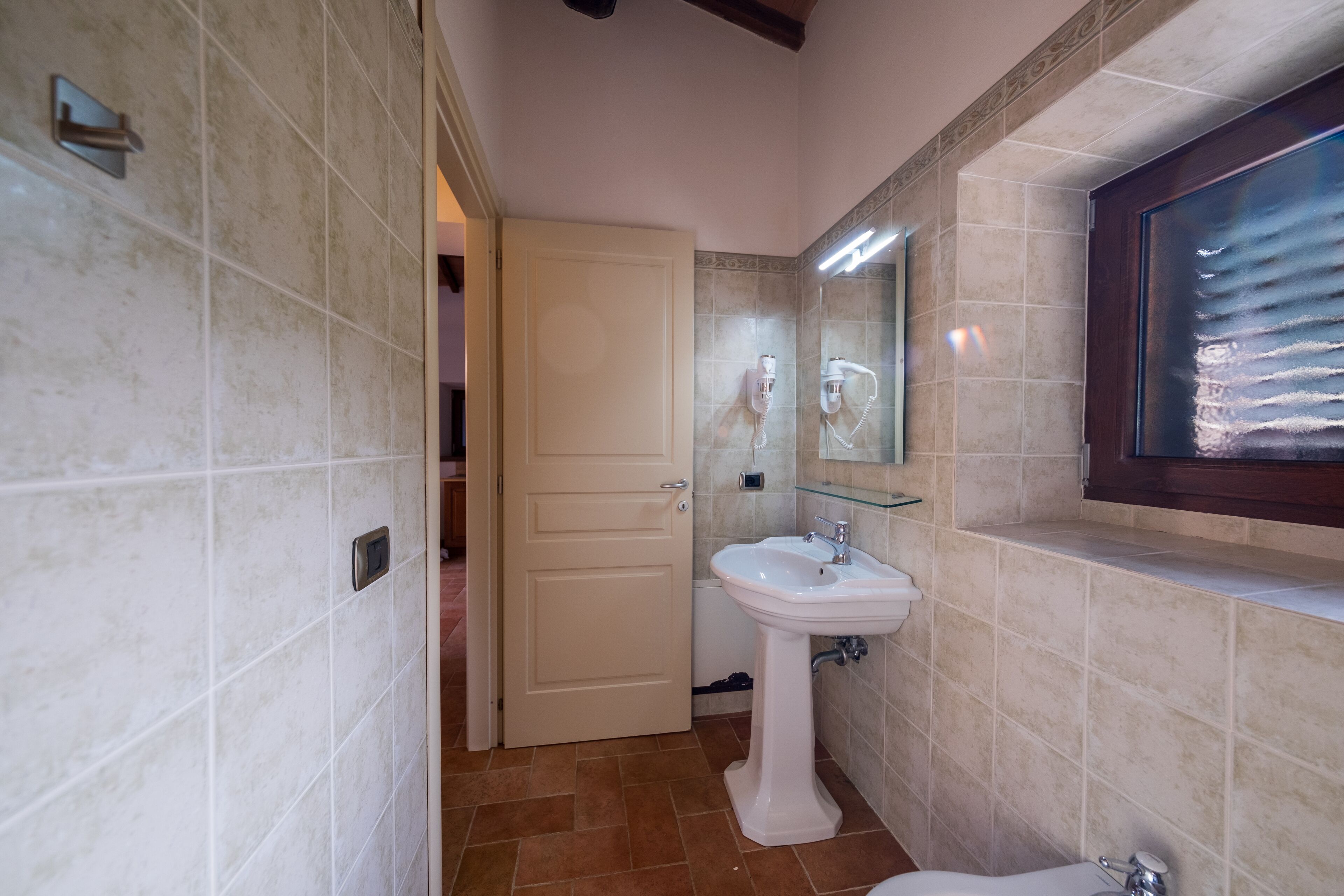Een badkamer met een witte wastafel, een spiegel en een douchehoek.