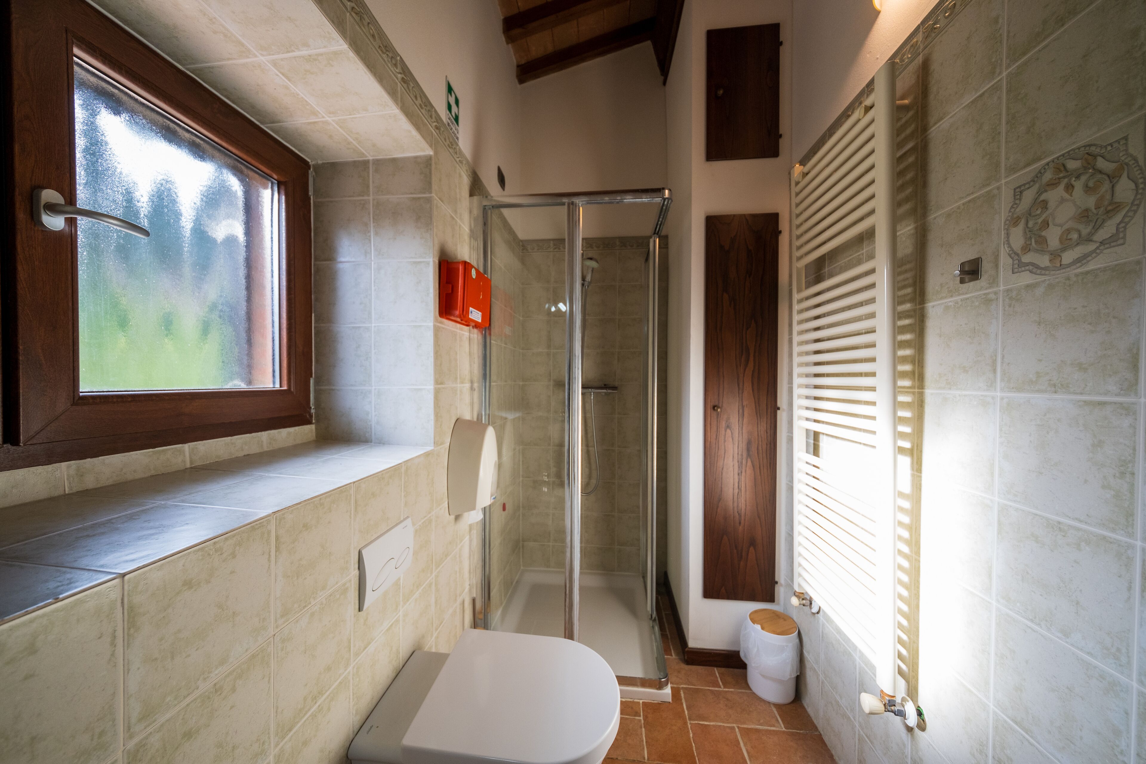 A bathroom with a shower, toilet, and window.