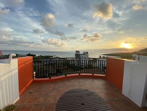 Un balcón con vista al mar y al atardecer.