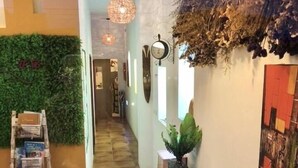 Un interior moderno con suelo de madera, sofá verde, escalera y pared decorada con plantas y obras de arte.