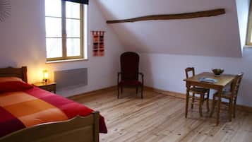 Ein Zimmer mit einem Bett, einem Tisch mit Stühlen, einem Fenster und einem Sessel.