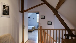 Une pièce avec un plafond en bois, un lit et une porte donnant sur une autre pièce.