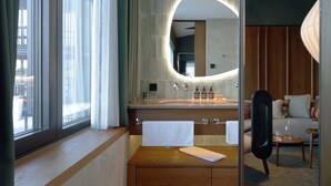 A modern hotel bathroom with a large mirror, a wooden vanity, and a window with curtains. - New Hotel Kristberg in Lech with Spa, outdoor pool and panoramic view (Lech am Arlberg)