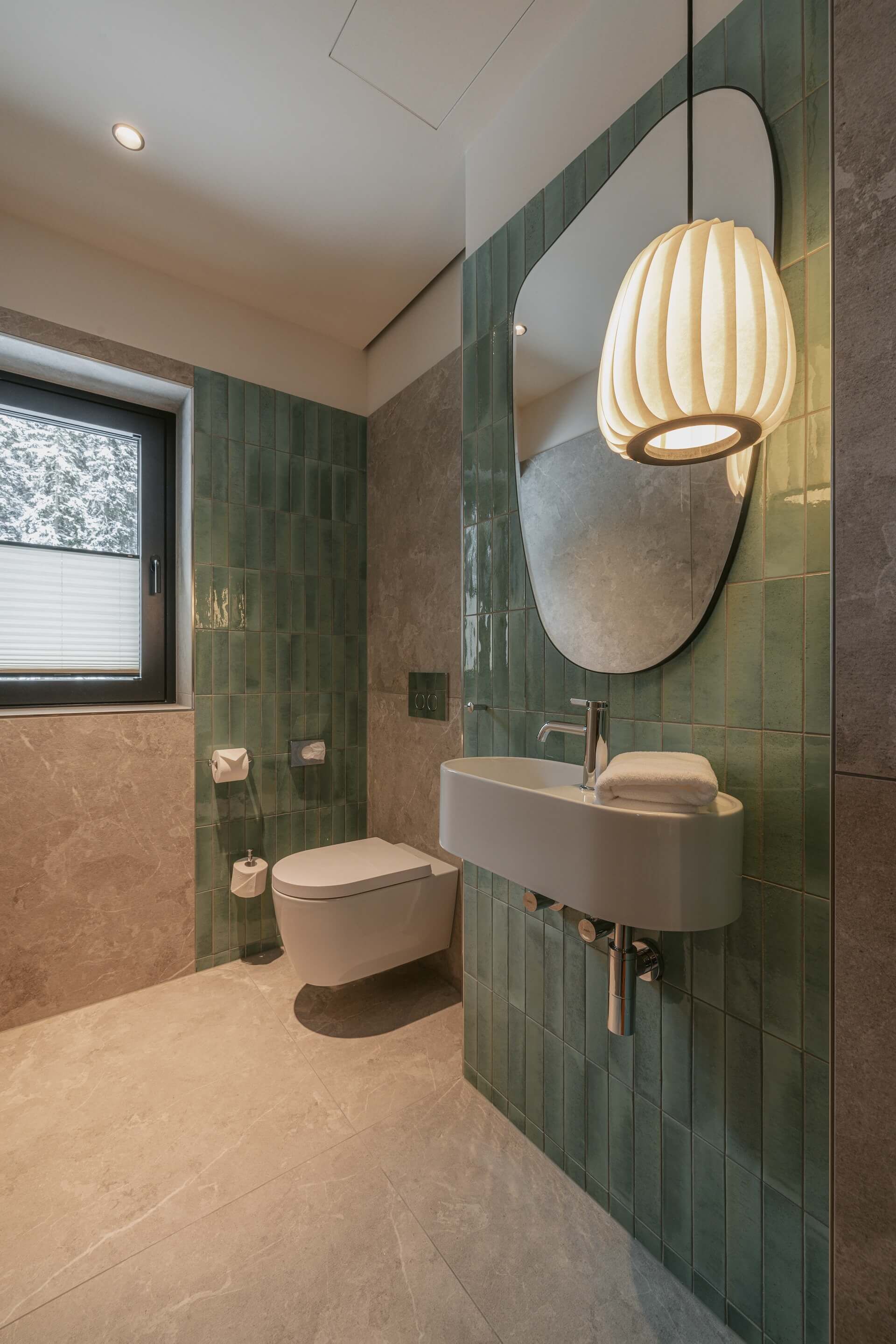 Un baño moderno con una bañera independiente, un espejo grande y un lavabo instalado en la pared.