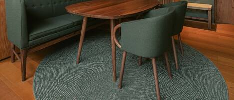 A modern interior with a sectional sofa, a round wooden table, and a green rug.