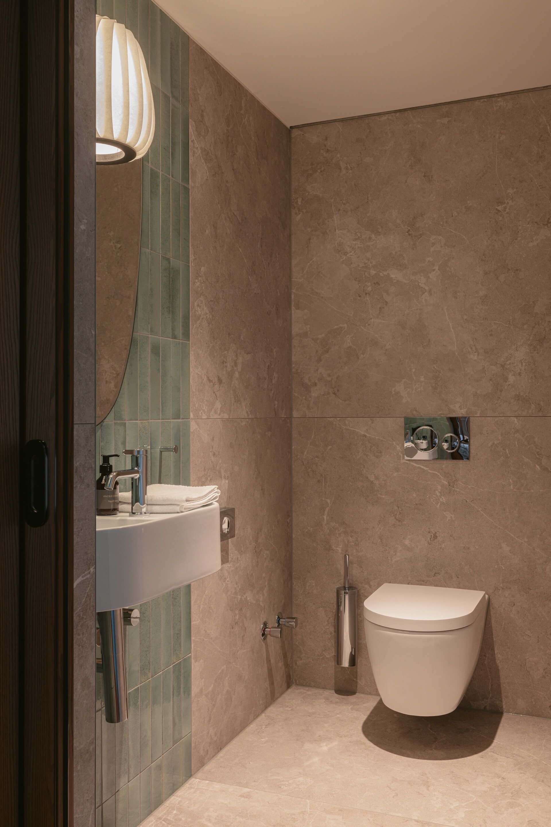 A modern bathroom with a white toilet, a sink with a mirror, and a shower area.